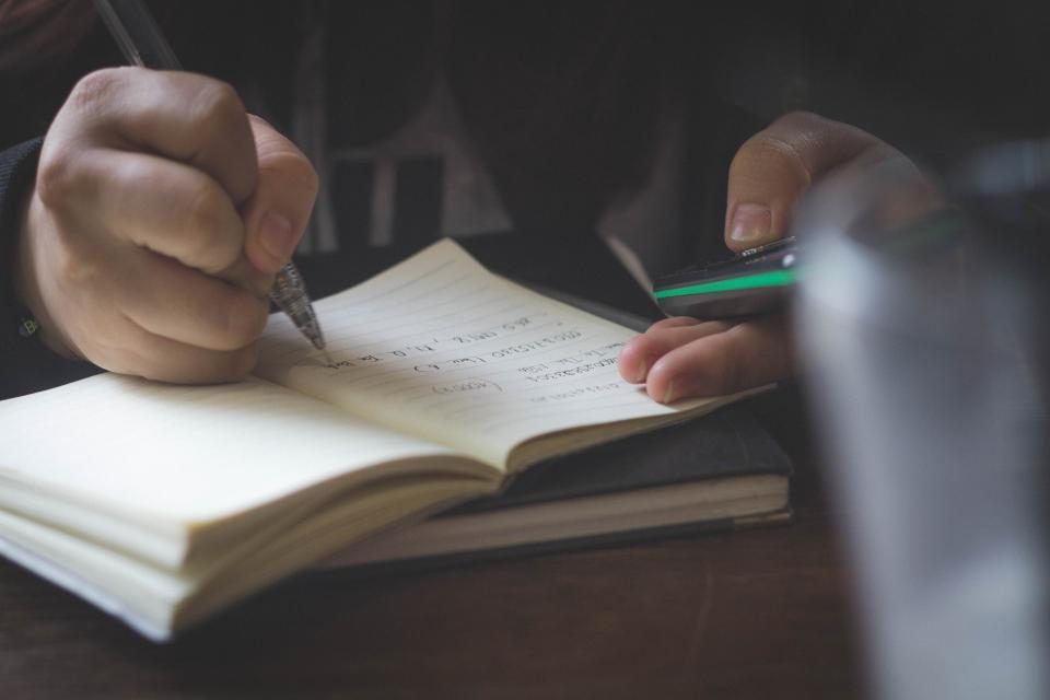 Cuaderno de notas escrito a mano durante una sesión de coaching, con calculadora al lado