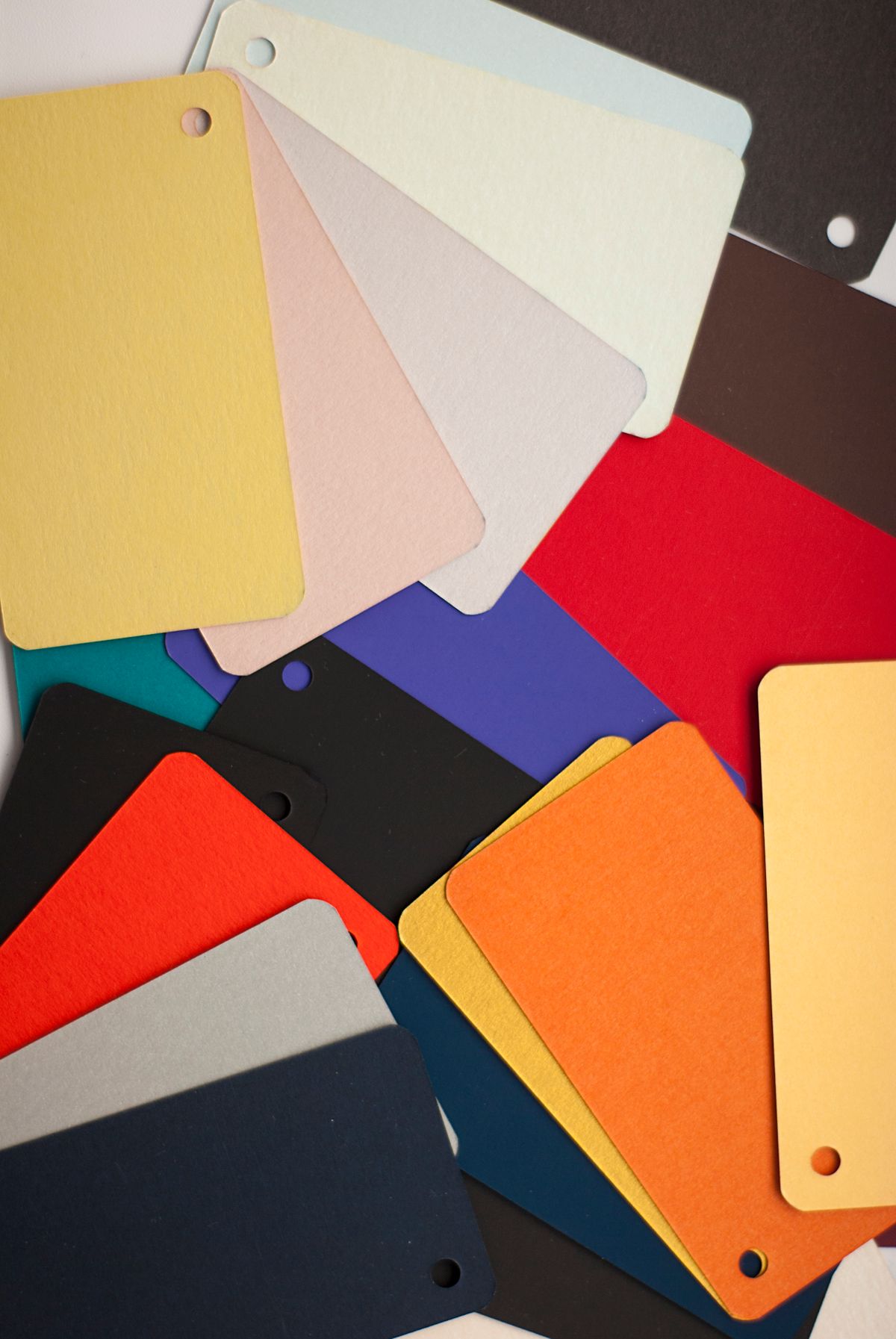 Muestras de cartulina de colores desparramadas sobre la mesa para cerrar la paleta de una marca