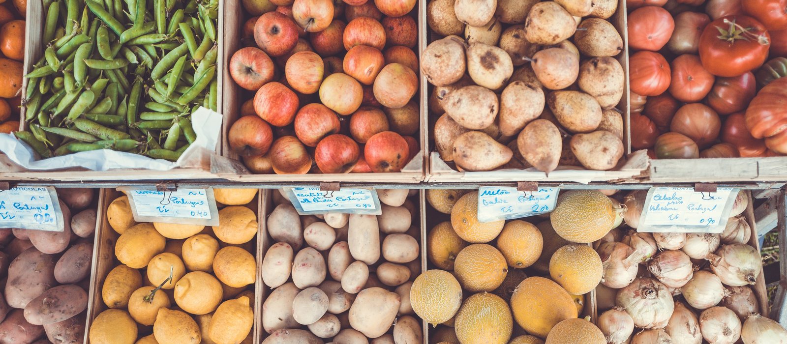 Cajones de un puesto de mercado con judías verdes, tomates, patatas, cebollas y limones